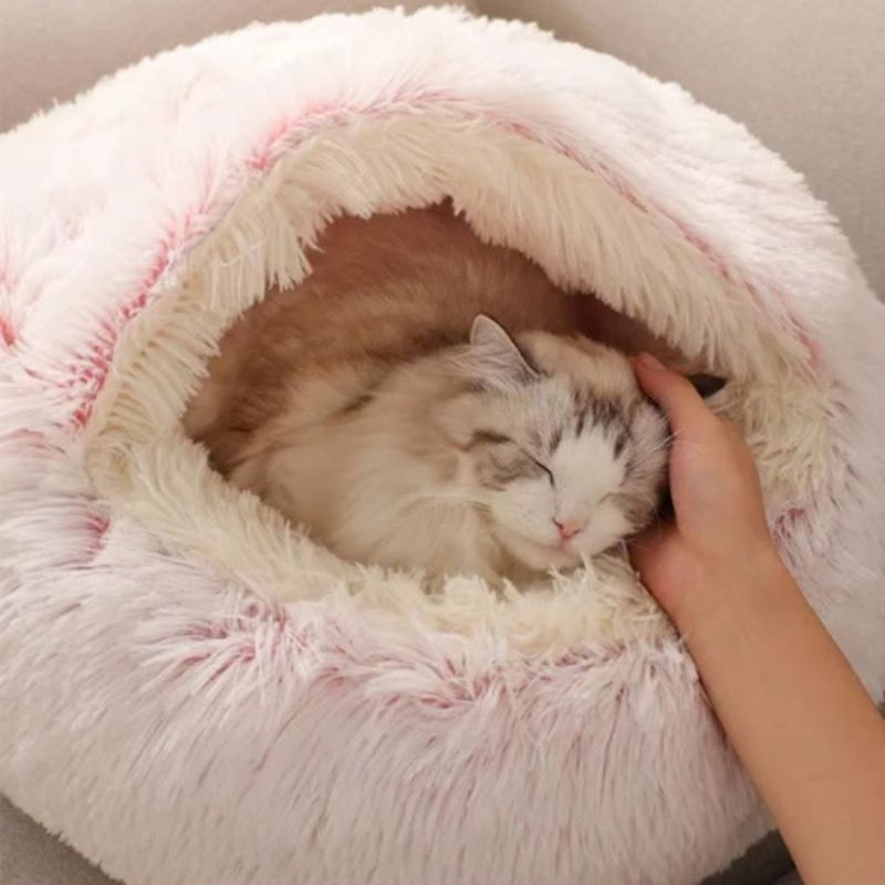Panier chat cocon rose avec un chat caressé à l’intérieur.