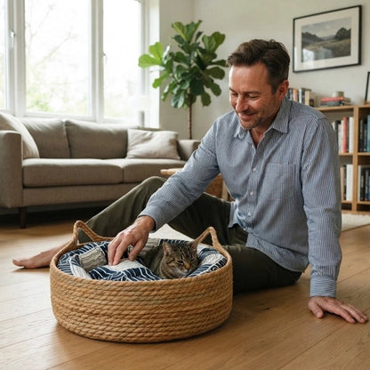 Chat tigré installé dans un panier en osier avec coussin bleu et blanc