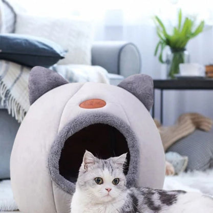 Panier pour chat grotte gris avec un chat allongé devant.