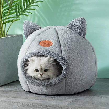 Panier pour chat grotte gris avec un chat blanc à l’intérieur.